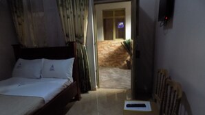 Un dormitorio con cama, una silla, un televisor y una puerta que da a un balcón.
