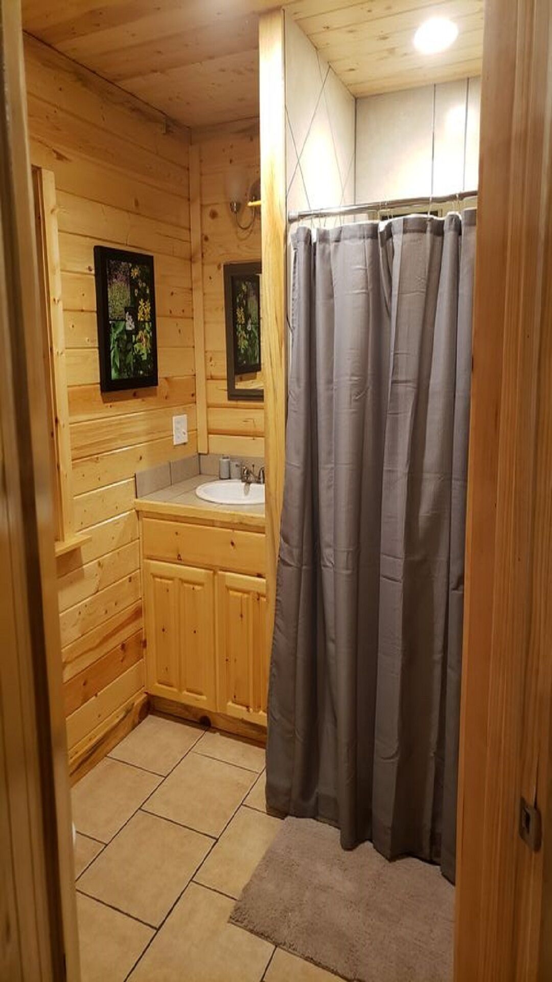 A wooden cabin bathroom with a sink, cabinets, and a shower curtain.
