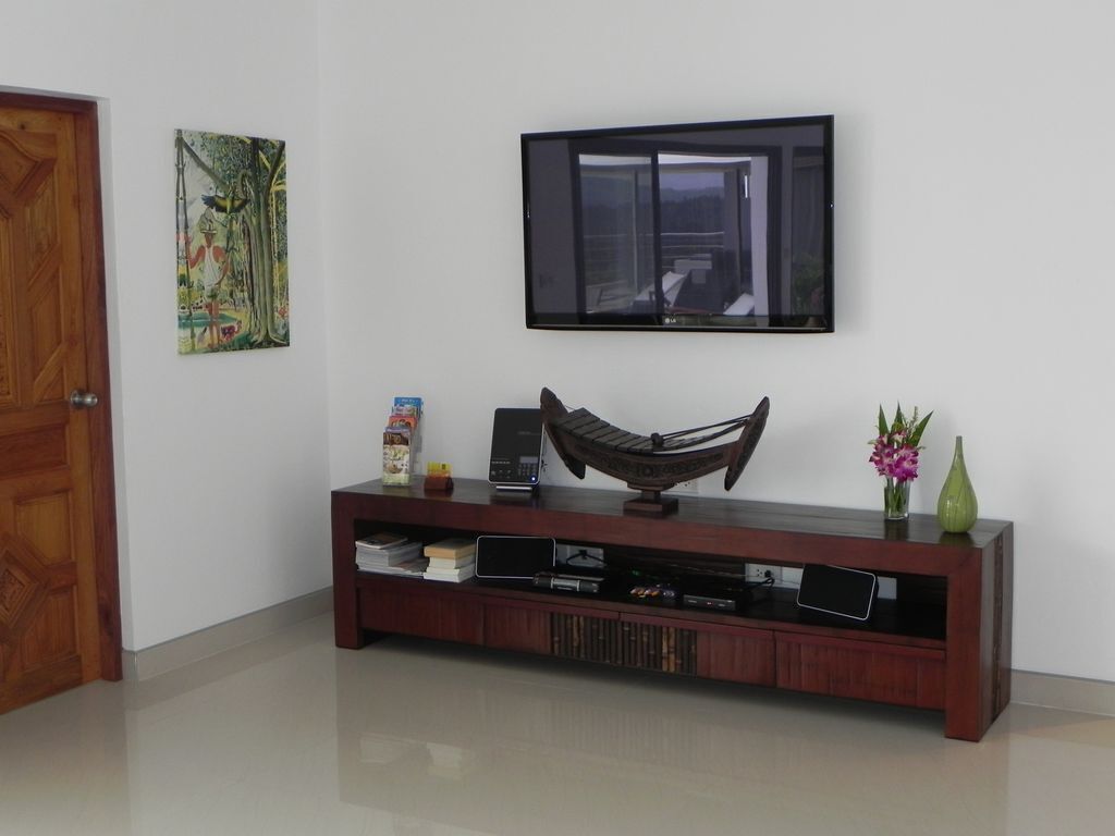 Un salon avec une console en bois, un téléviseur à écran plat fixé au-dessus et un hamac posé sur la console.