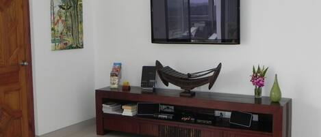Un salon avec une console en bois, un téléviseur à écran plat fixé au-dessus et un hamac posé sur la console.