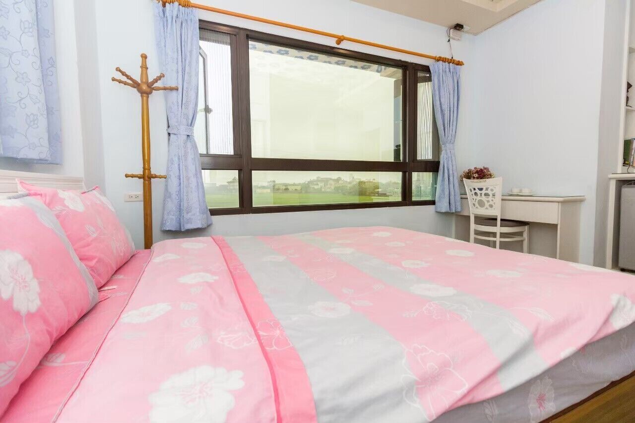 A bedroom with a bed, a desk, and a chair.