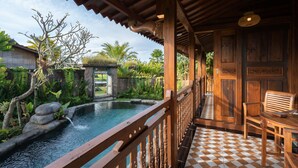 A wooden deck with a checkered floor, a pool, and a chair. - Uma Sebatu Villas Ubud (Sebatu)