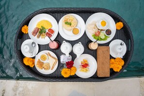 A breakfast tray with various dishes and drinks by a pool. - Uma Sebatu Villas Ubud (Sebatu)
