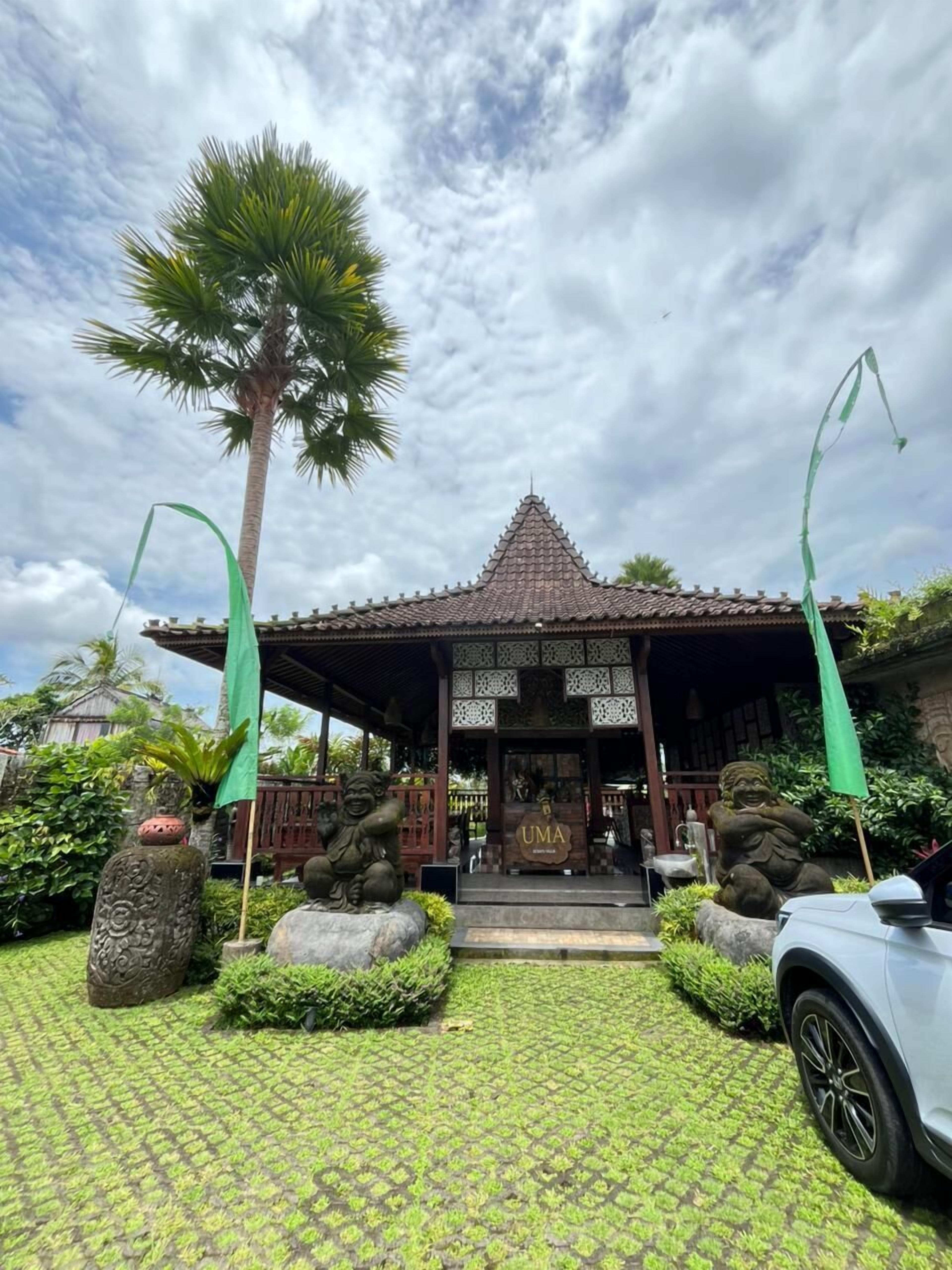 A traditional building with a tiled roof, surrounded by greenery and a patterned pavement.