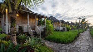 A traditional wooden house with a porch, surrounded by lush greenery and a stone pathway. - Uma Sebatu Villas Ubud (Sebatu)