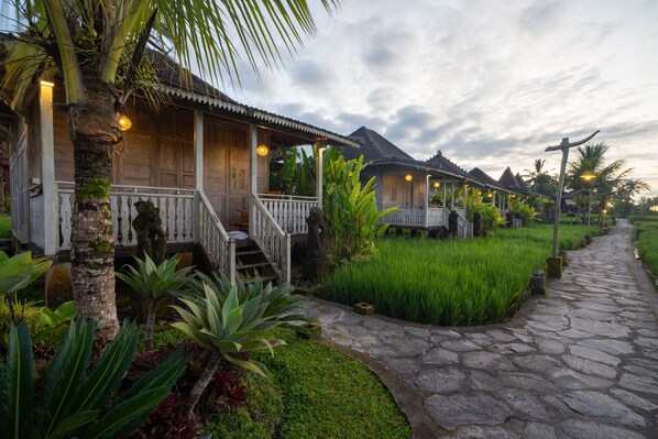 A traditional wooden house with a porch, surrounded by lush greenery and a stone pathway. - Uma Sebatu Villas Ubud (Sebatu)
