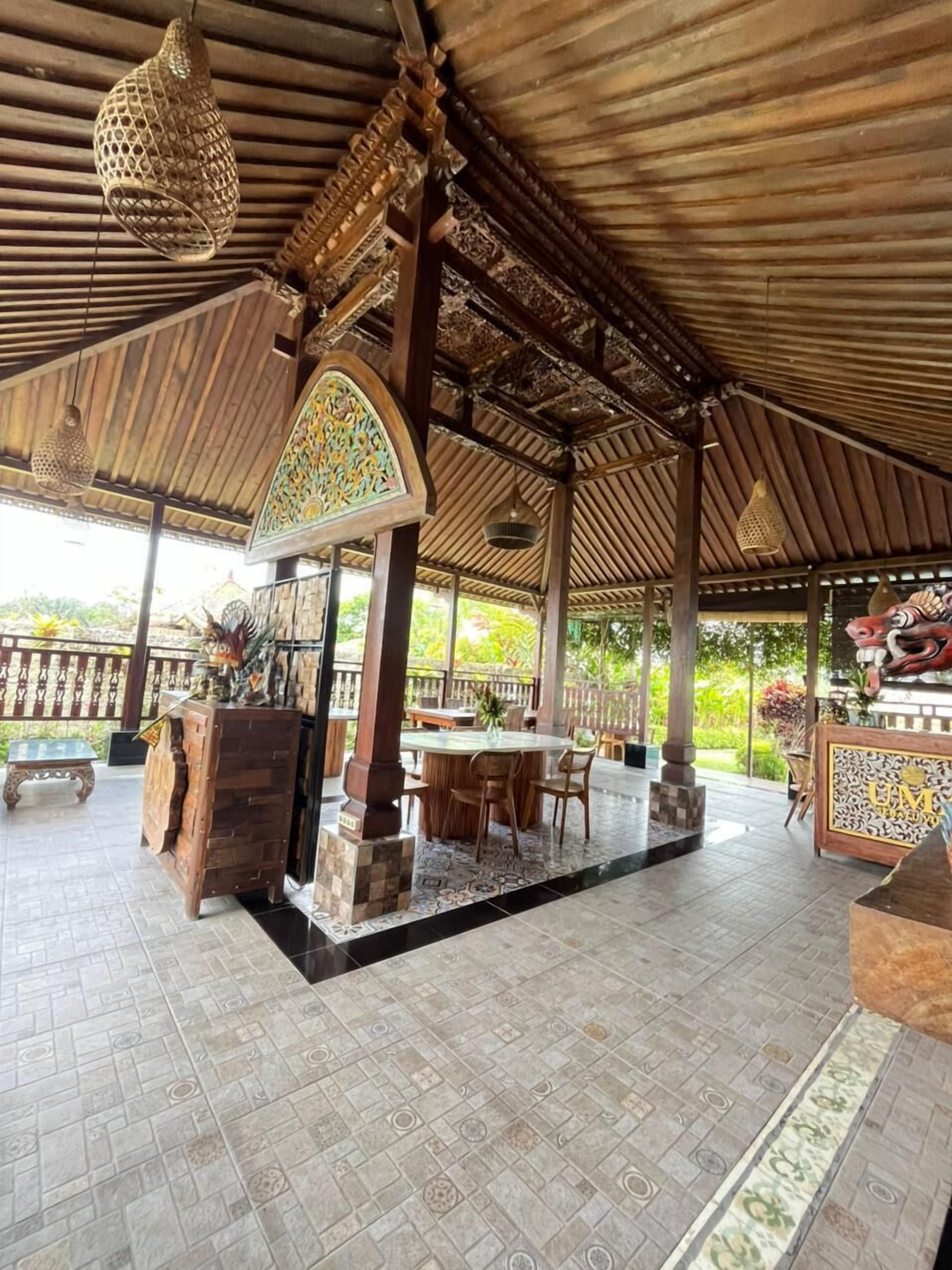 A covered outdoor area with a wooden ceiling, a central table with chairs, and a decorative archway.