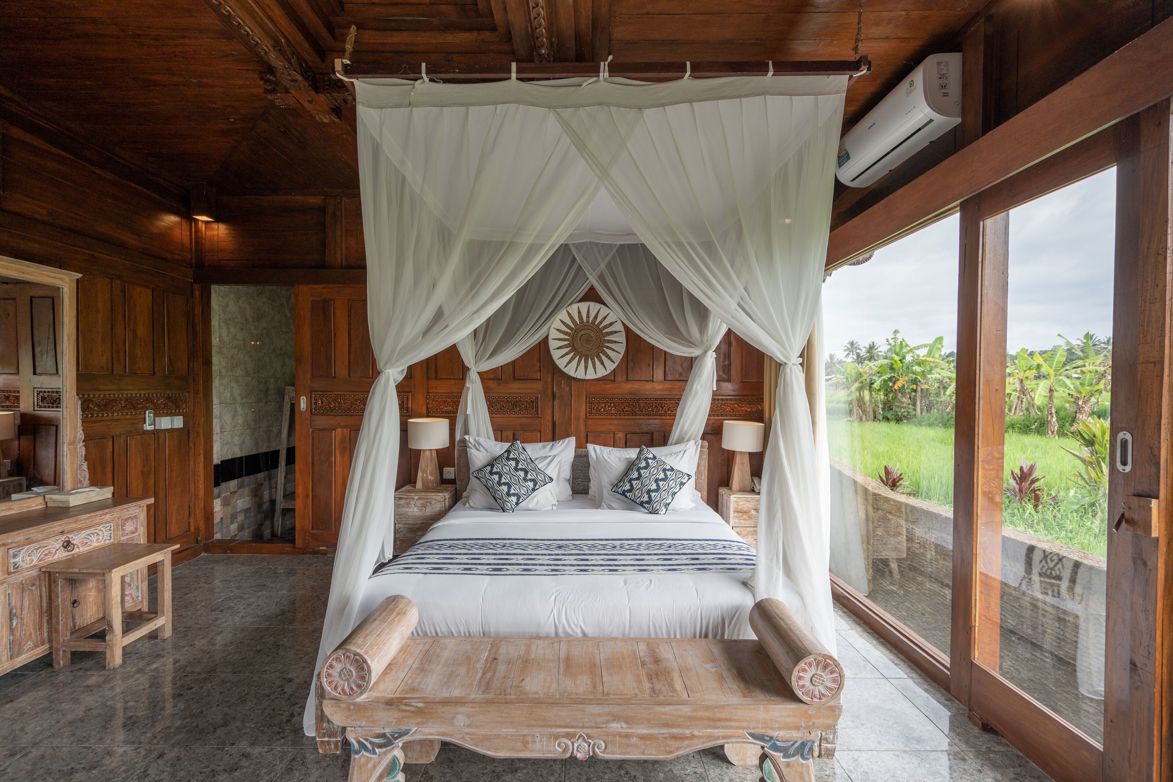 A large bed with a canopy, wooden headboard, and decorative pillows.