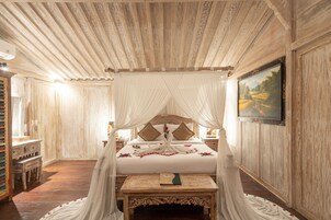 Una cama con dosel y pilares, un cabecero de madera, una mesita de noche y un cuadro en la pared.