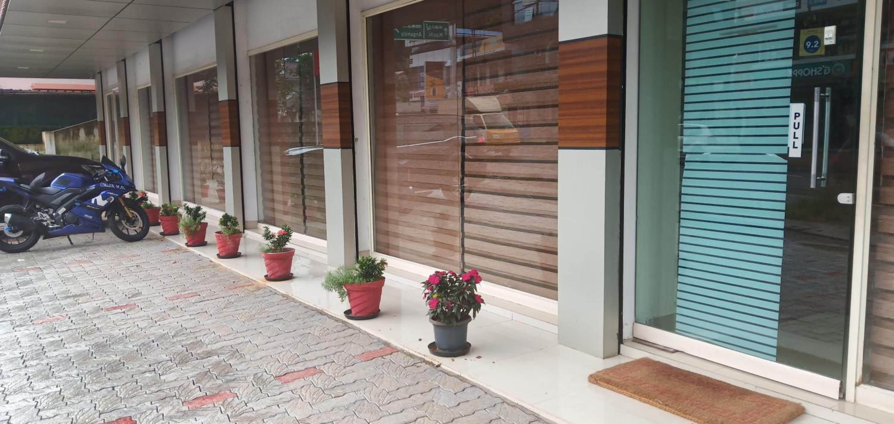 A building with a covered entrance, potted plants, and a blue sliding door.