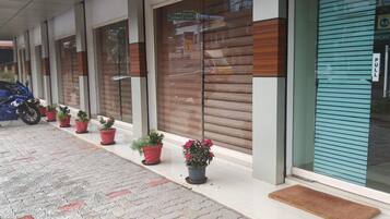 A building with a covered entrance, potted plants, and a blue sliding door.