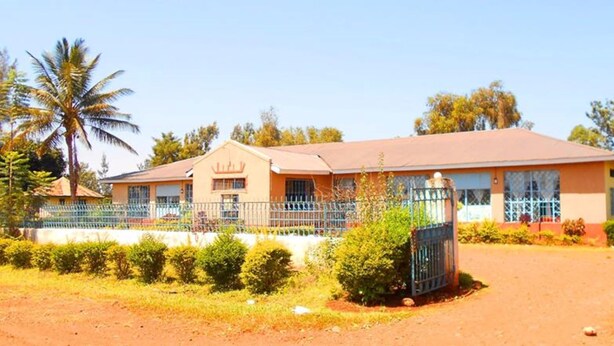 A two-story building with a flat roof, a gated entrance, and a paved driveway.