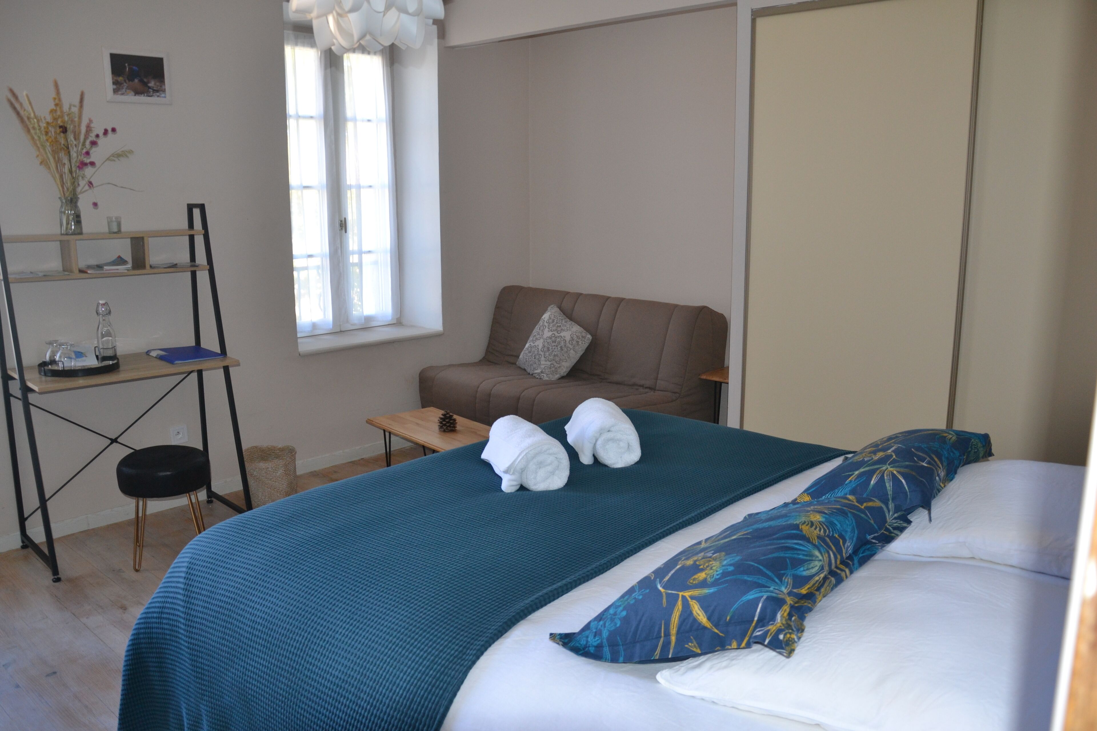 Une chambre à coucher avec un lit, un canapé, une petite table et une fenêtre.