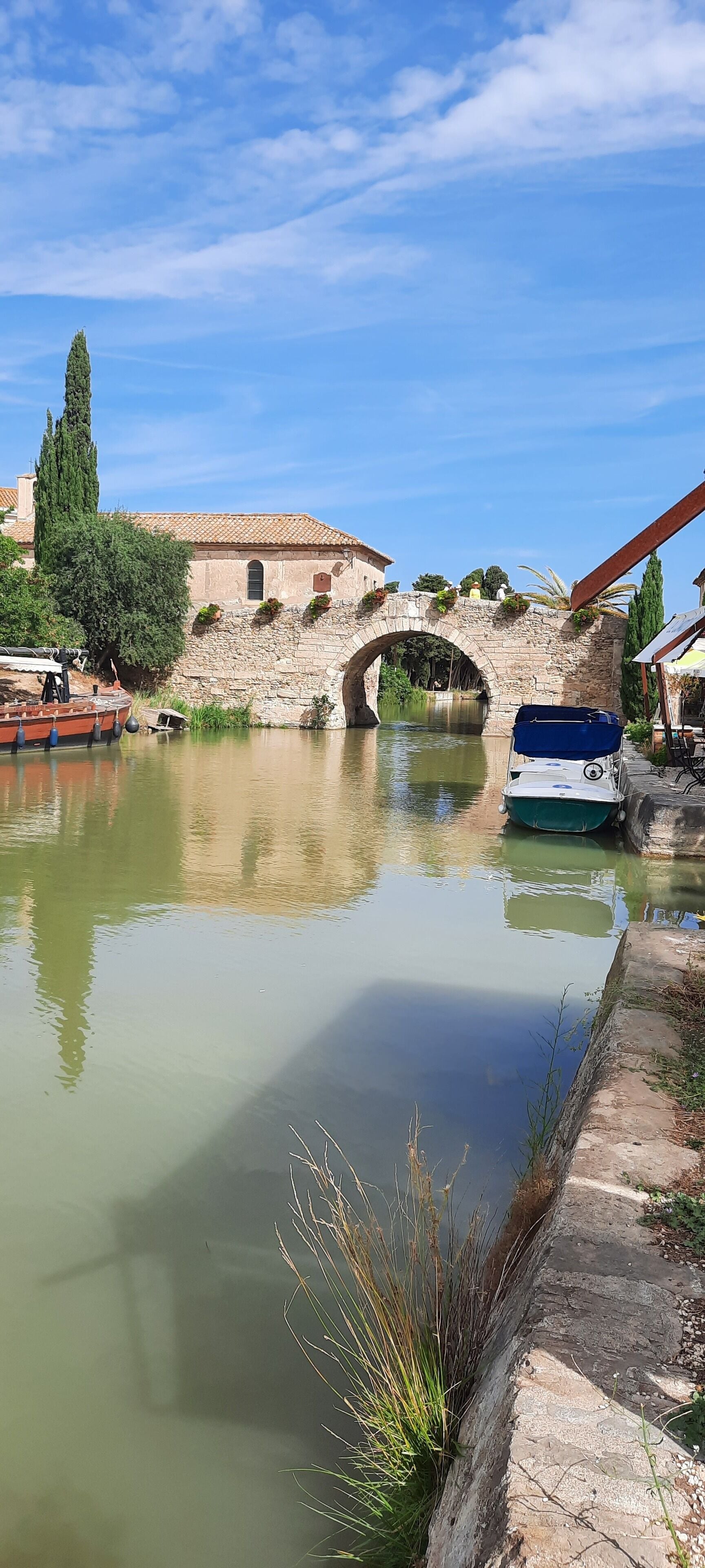 Un canal con un puente de piedra, barcos y edificios al fondo.