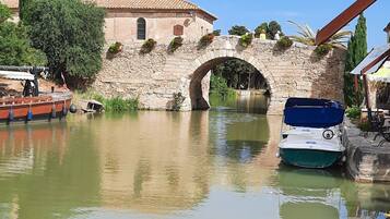 Un canal con un puente de piedra, barcos y edificios al fondo.