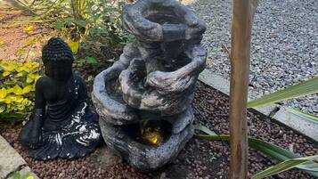 Un giardino con una statua di Buddha, una fontana di pietra e un albero.