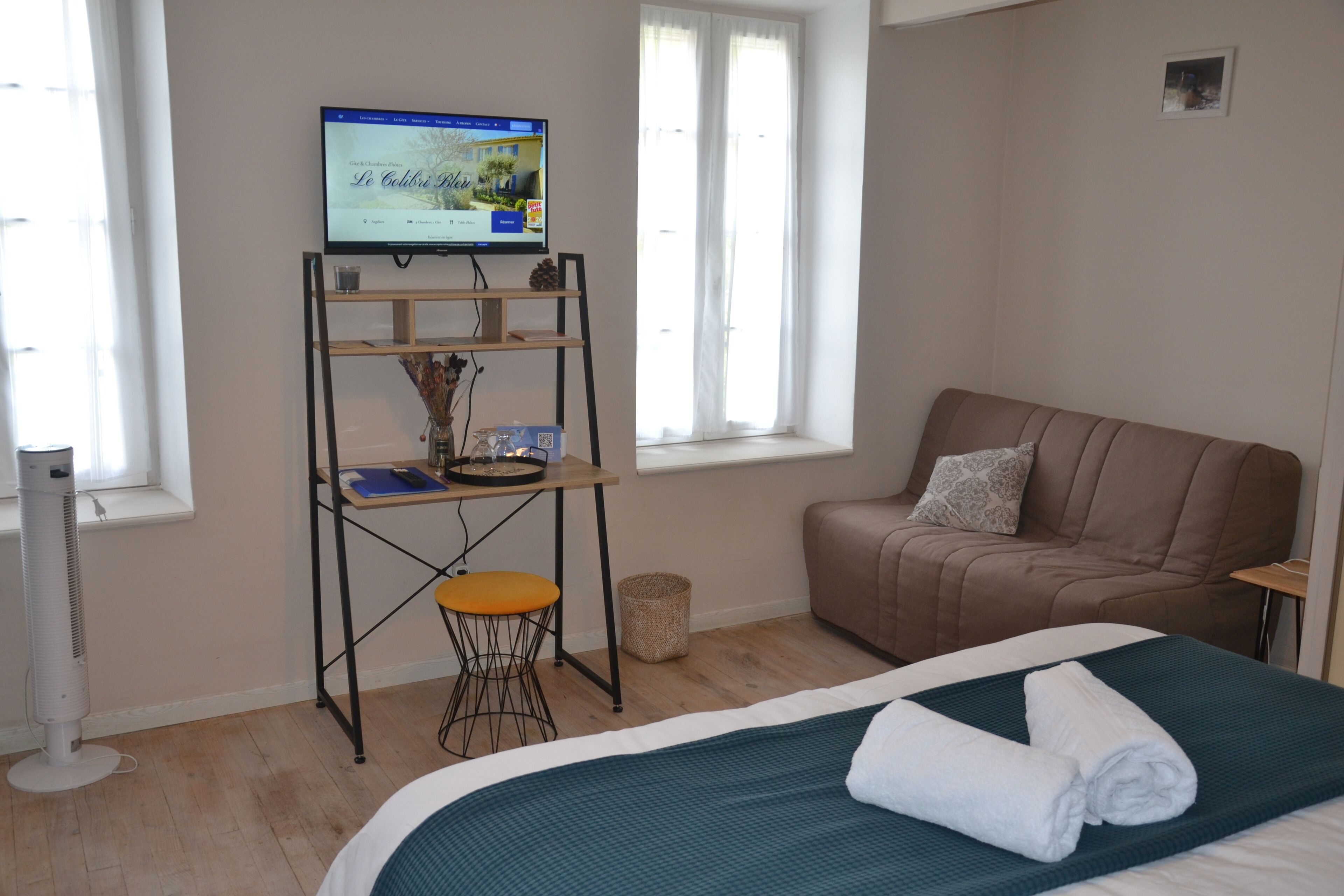 Une chambre d’hôtel avec un lit, un canapé, un téléviseur posé sur un meuble et une fenêtre.