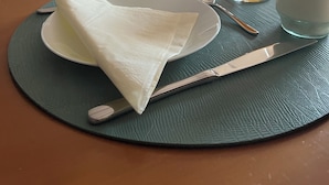 Una mesa de desayuno dispuesta con platos, vasos y cubiertos, que indica un comedor en un hotel.