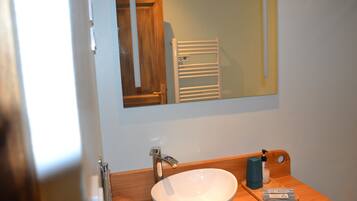 A bathroom with a white sink, a wooden vanity, a mirror, and a towel rack.