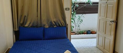 A bedroom with a bed, curtains, and a door.