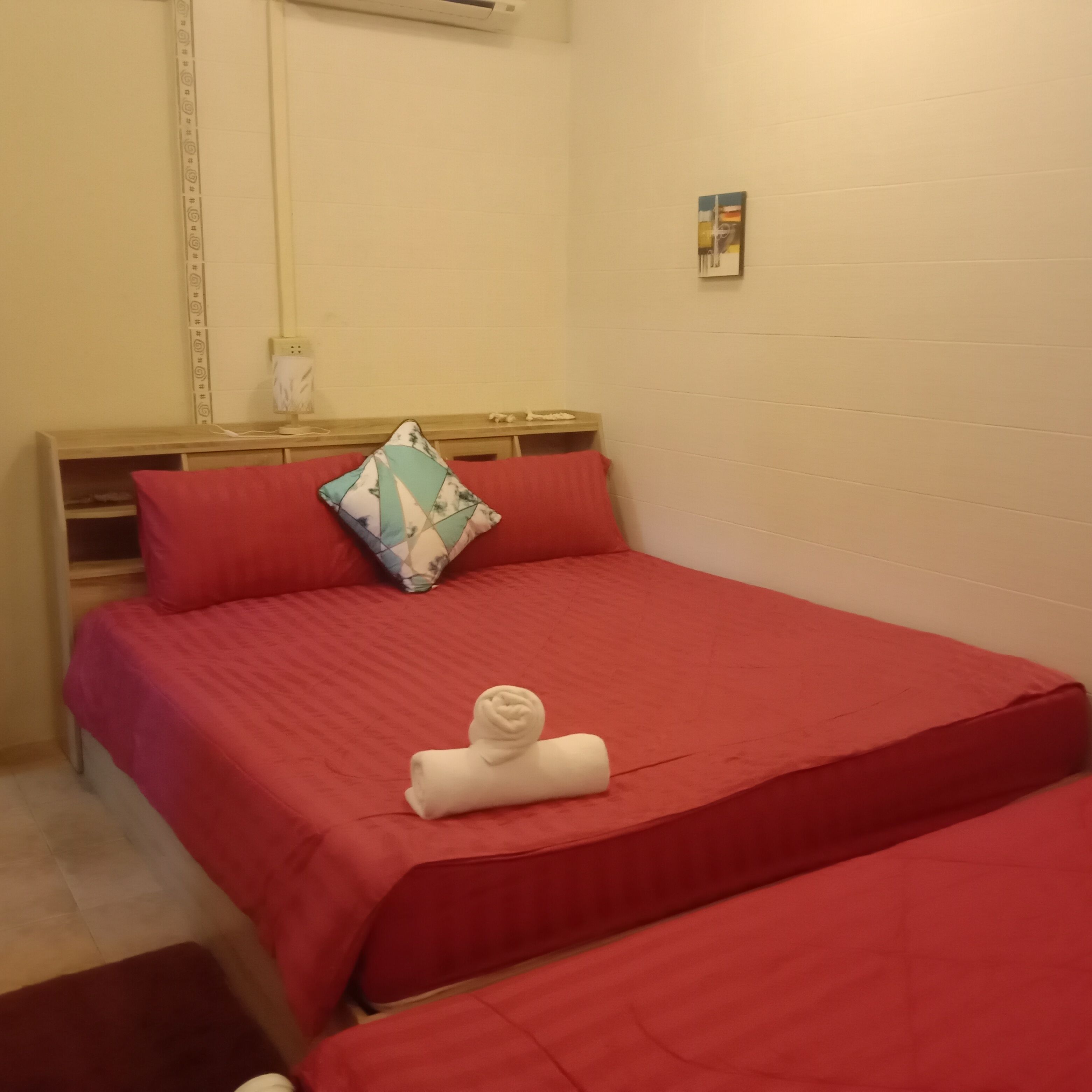 A room with a bed, a bedside table, a pillow, and a towel.