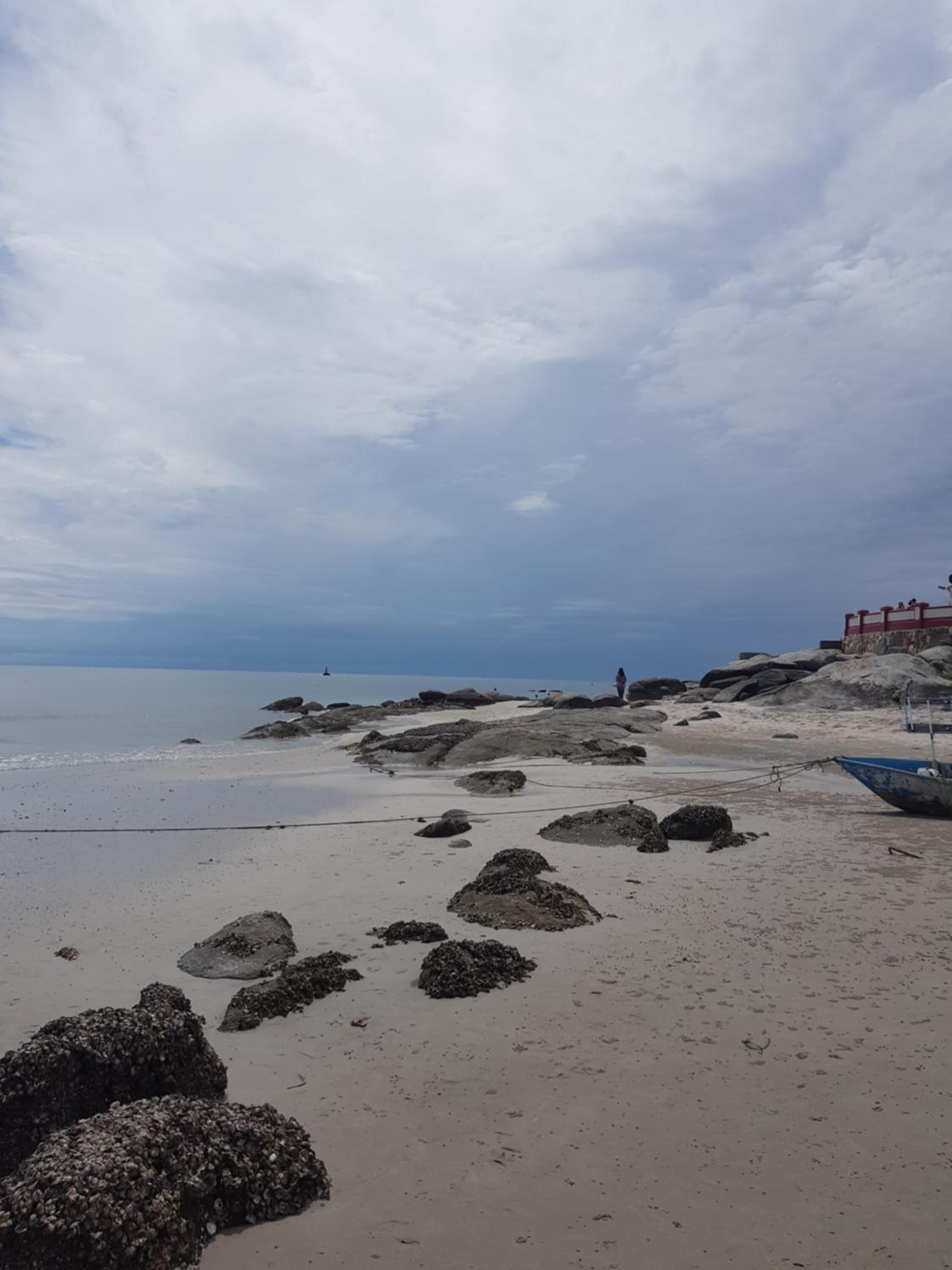 Una playa con rocas grandes y un bote.