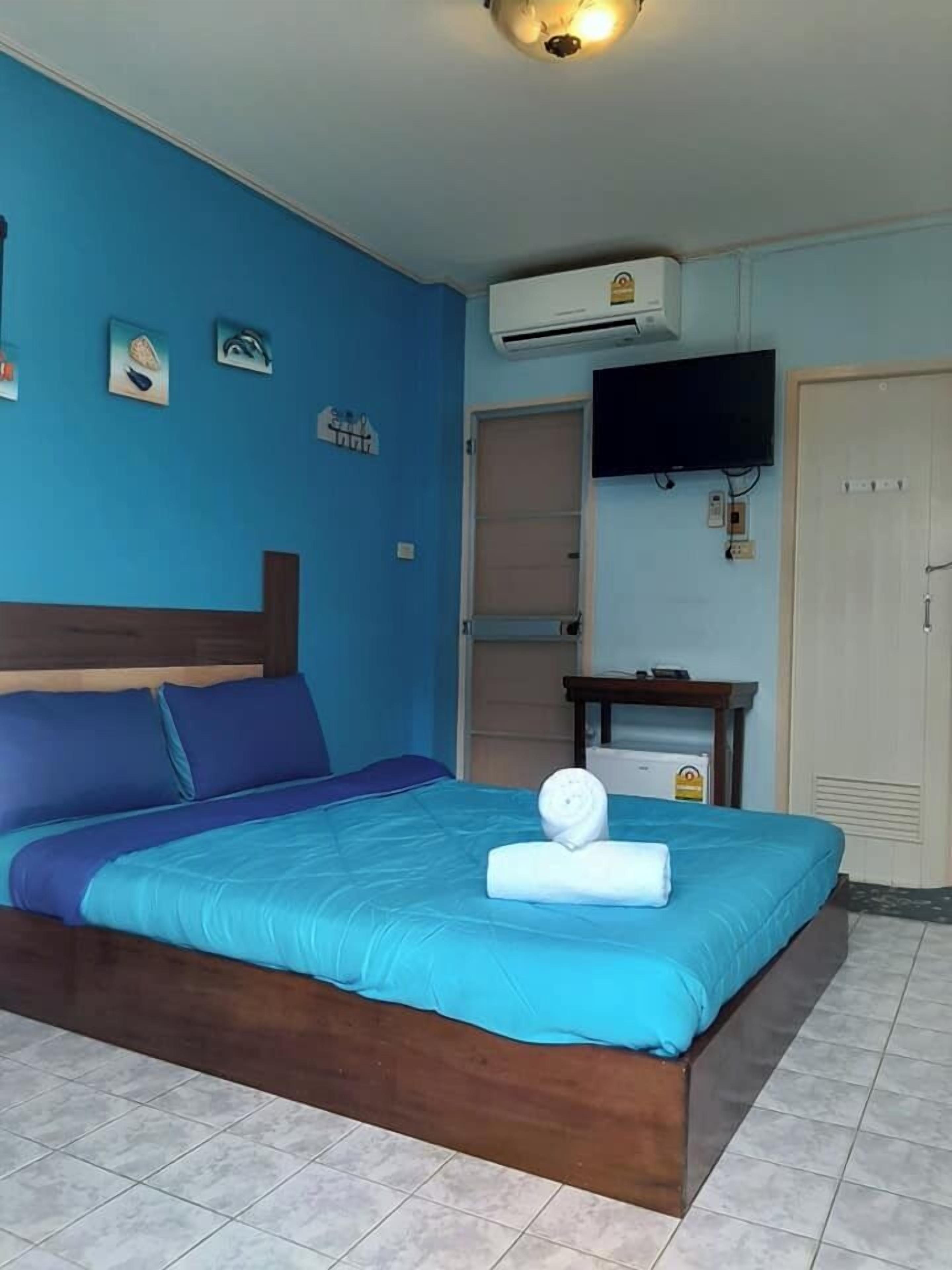 Une chambre avec un lit, un téléviseur à écran plat, un appareil de climatisation et une petite table.