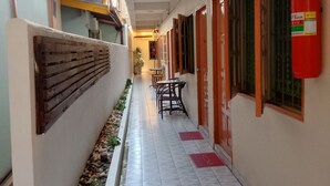 A narrow corridor with tiled flooring, wooden benches, and a fire extinguisher on the wall. - Plaza Hua Hin (Hua Hin)