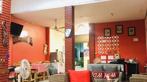 A spacious indoor area with wicker furniture, red cushions, and a tiled floor. - Plaza Hua Hin (Hua Hin)