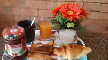 Bandeja de desayuno con tostadas, un croissant, un vaso de jugo de naranja, una taza y un frasco de mermelada.