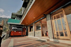 The Griffin's Nest Hotel & Restaurant with a wooden facade, large windows, and a stone wall. - The Griffon's Nest (Gangtok)