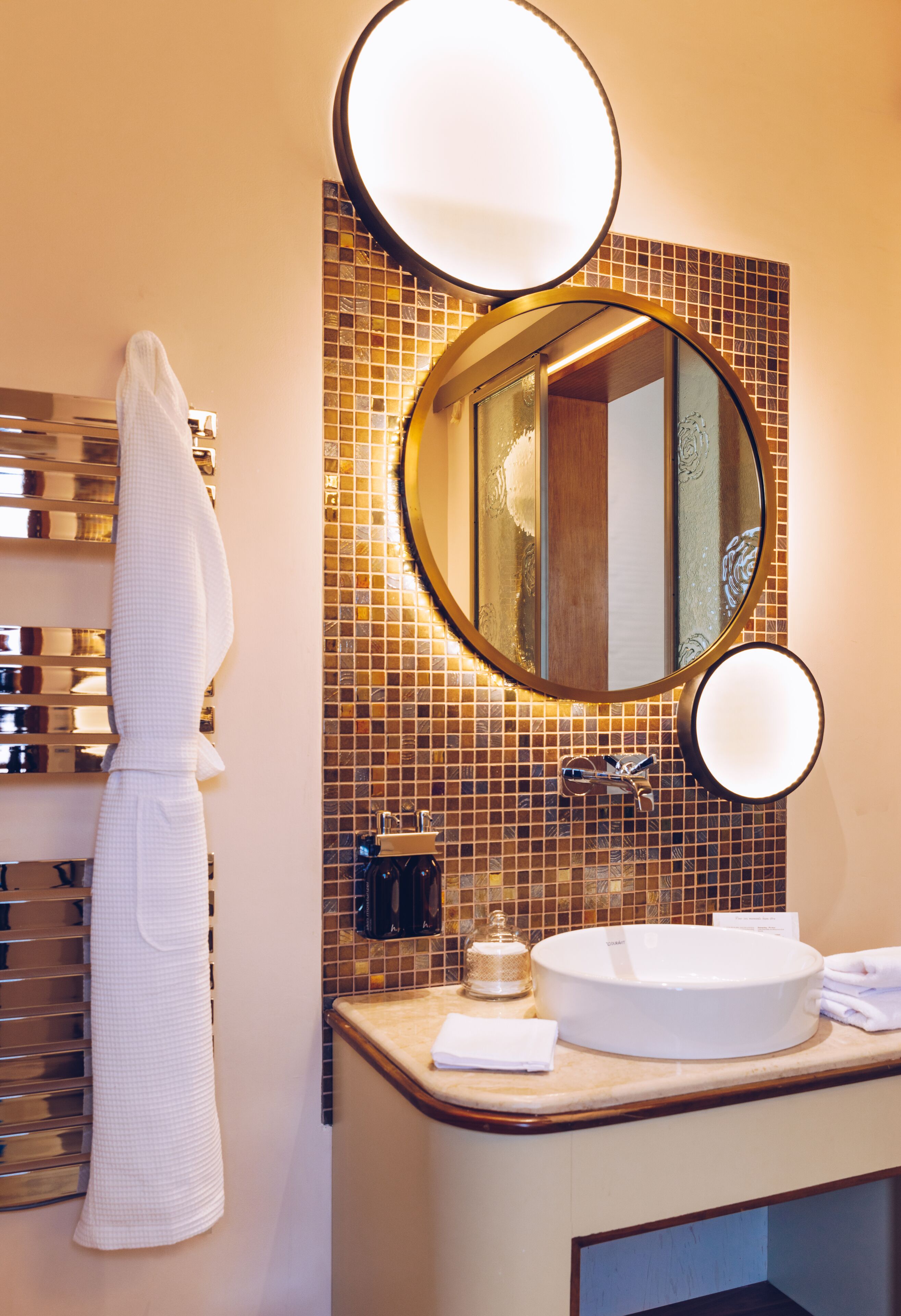 Ein Badezimmer mit einem großen Spiegel, einem Handtuchhalter und einem Waschbecken mit einer Shampooflasche.