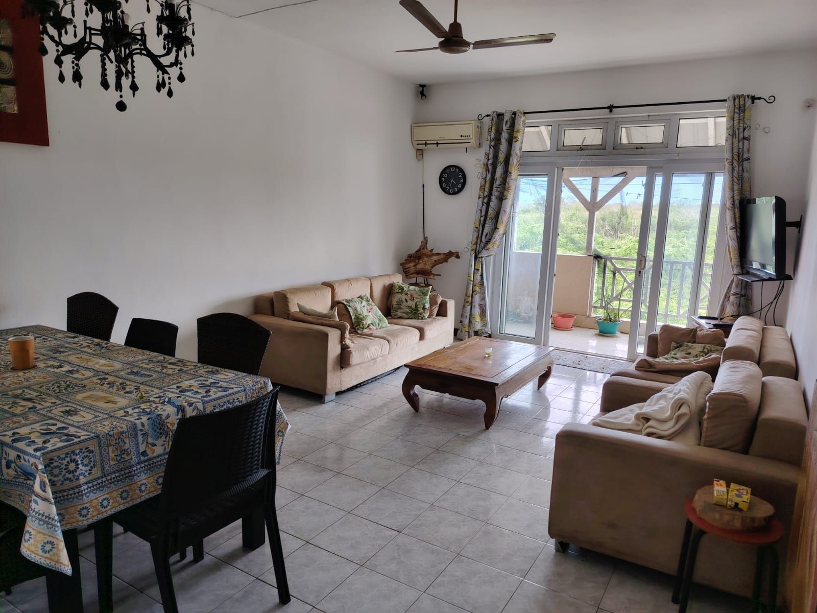 Una sala de estar con sofá, mesa de centro, mesa de comedor, sillas y televisor.