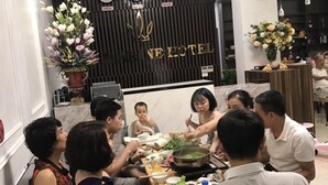 A group of people dining at a table in a hotel restaurant with a modern interior, including a clock and a sign that reads "NE HOTEL". - The Marine Hotel (Bai Chay)