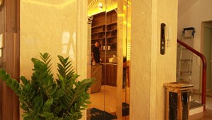 An elevator with a marble wall, a potted plant, and a staircase with a red handrail. - The Marine Hotel (Bai Chay)