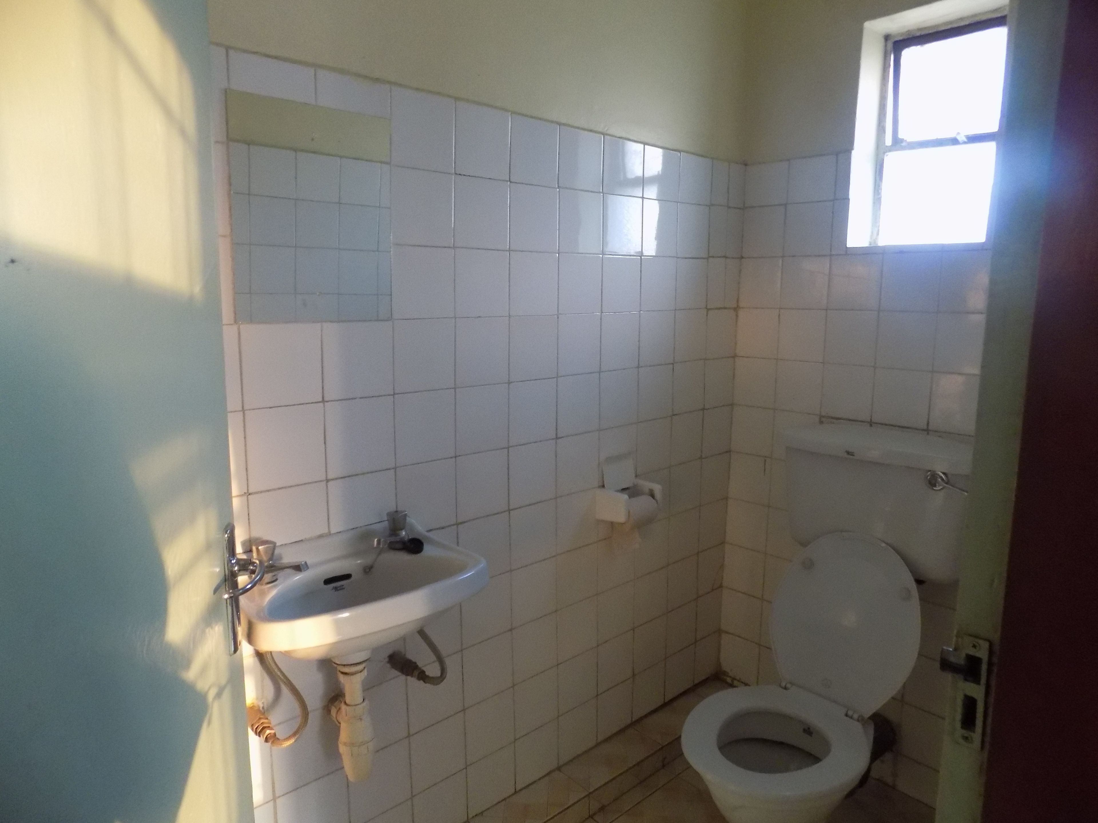 A bathroom with white tiles, a sink, and a toilet.