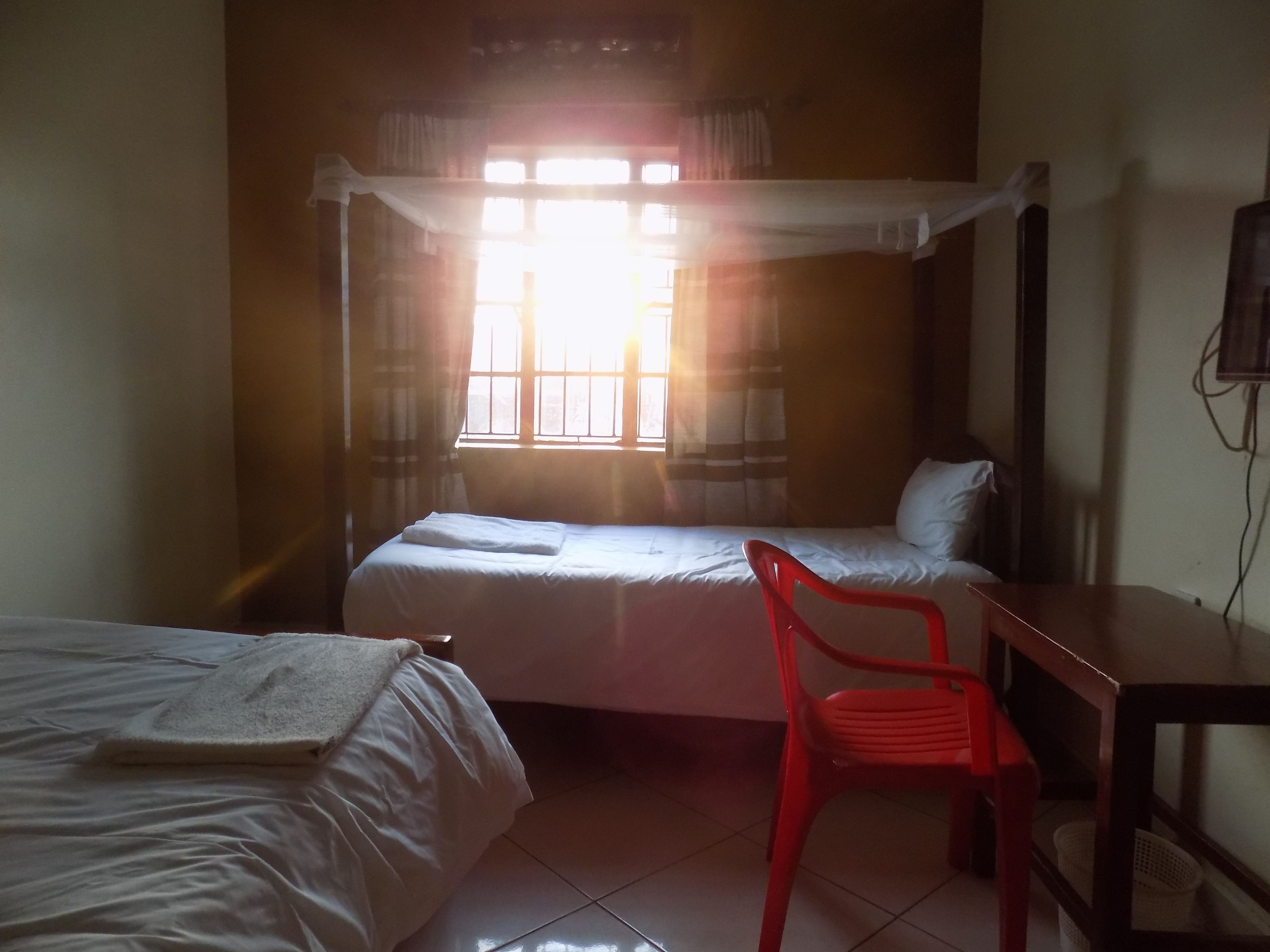 Una habitación con dos camas, una silla roja y un escritorio.