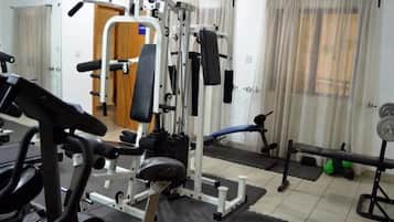 Une salle de sport équipée de matériel d’exercice, d’un banc et d’un support à poids.