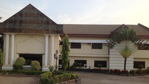 A building with a large central entrance, a smaller entrance with a triangular roof, and a fan-shaped roof on the right. - Eastern Comfort and Suites (Umuahia)