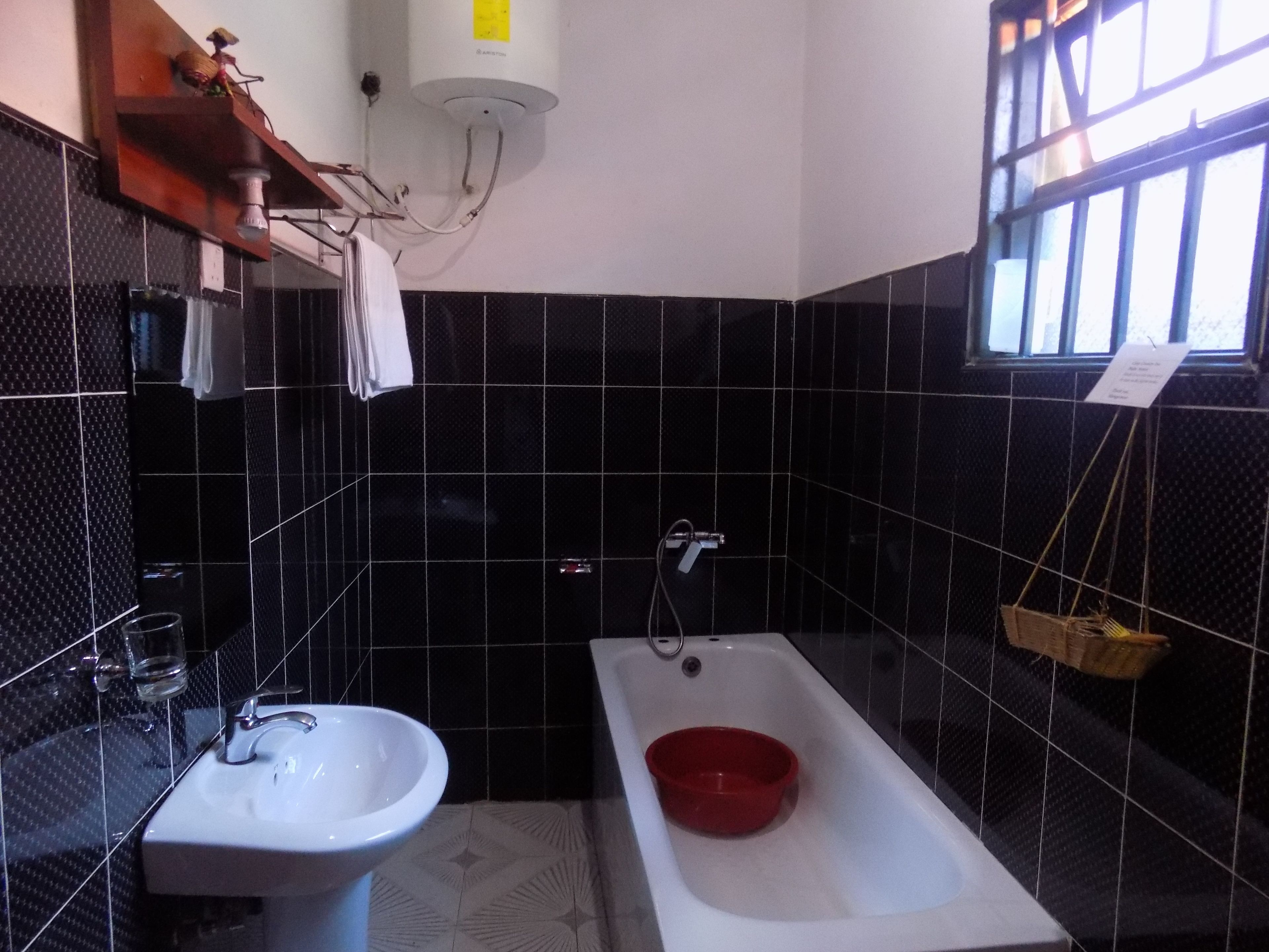 A bathroom with a white sink, a red basin, and a bathtub.