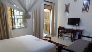A hotel room with a bed, a desk, a chair, a television, and a window with curtains. - Cielo Country Inn (Ishaka)