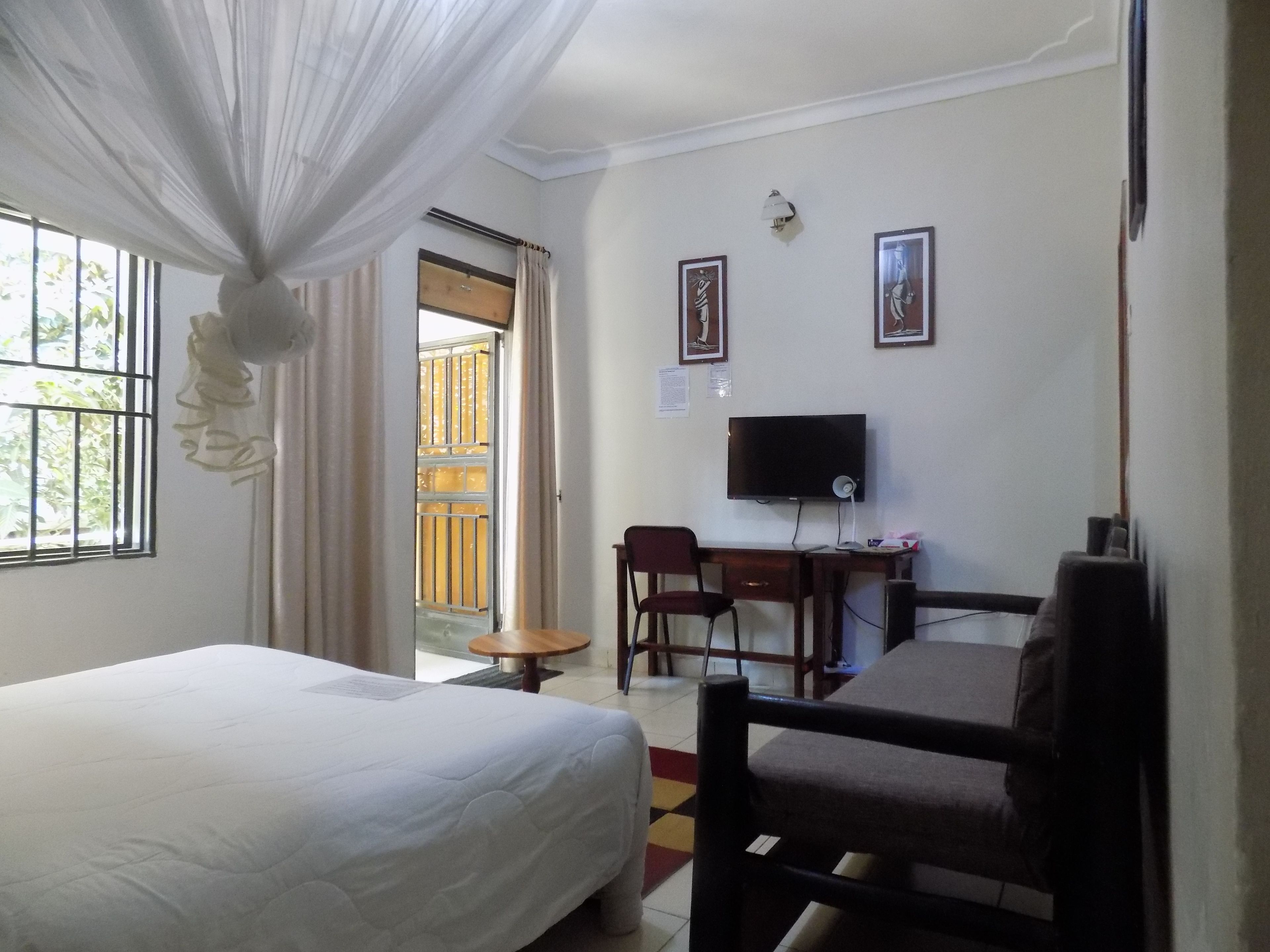 A hotel room with a bed, a desk with a computer, a chair, and a TV.