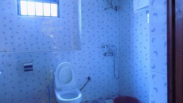 Un baño con inodoro, ducha y ventana.