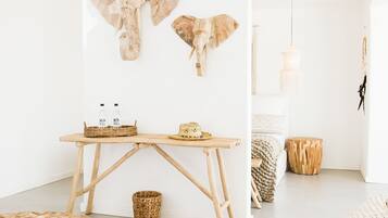 Una sala de estar moderna y minimalista con una mesa de centro de madera, una silla de mimbre y un sofá con un cojín estampado.