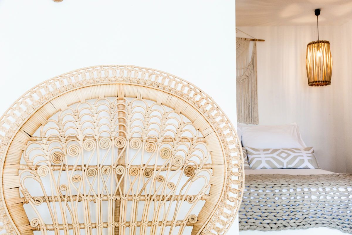 A rattan headboard with a circular design, a bed with patterned bedding, and a hanging light fixture.