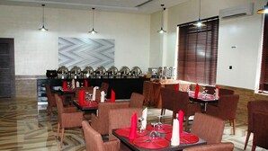 A restaurant with marble flooring, red napkins, and modern lighting.