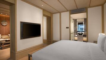 Habitación de hotel con una cama grande, un televisor de pantalla plana en la pared, una mesita pequeña y un espejo.