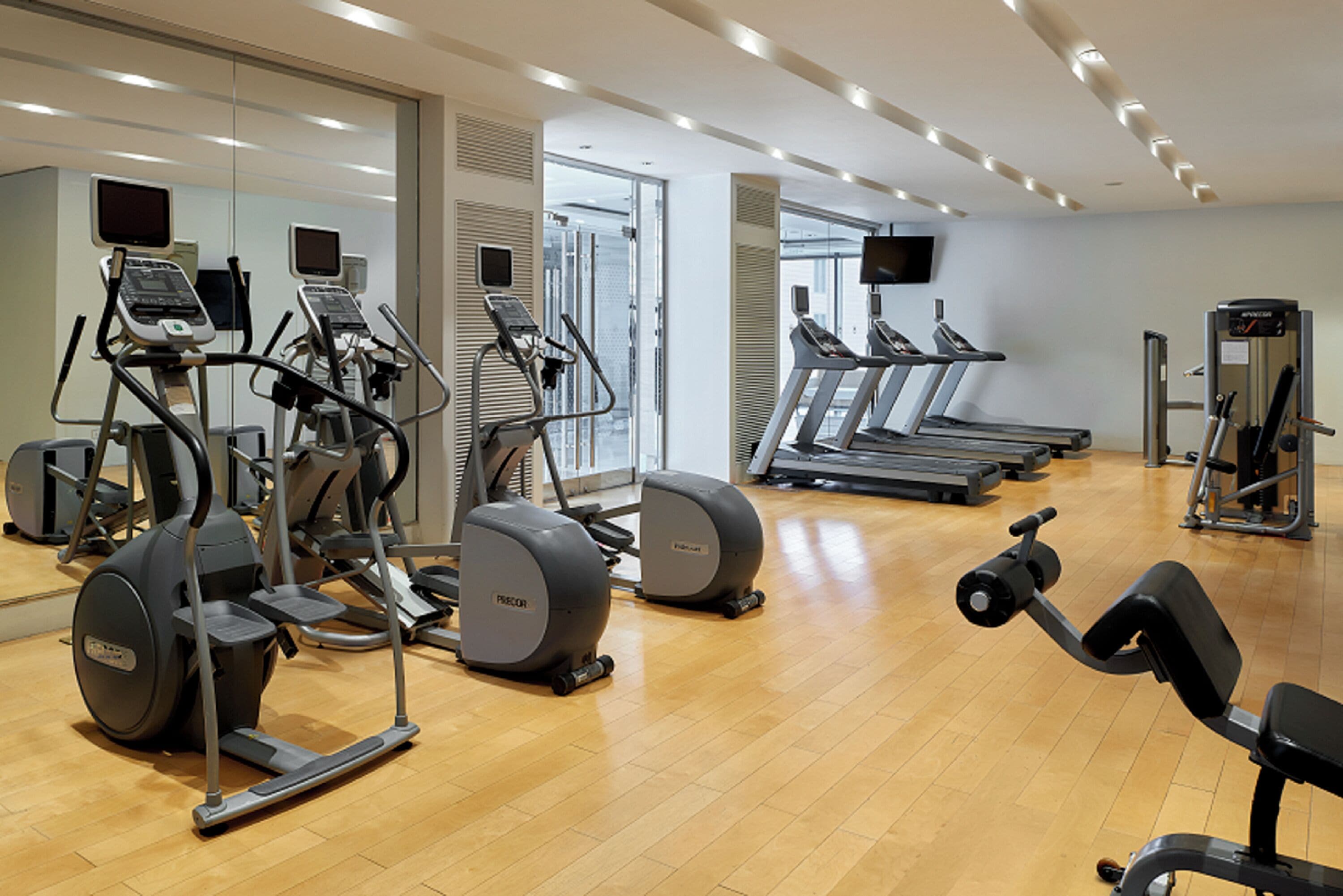 A gym with cardio machines, weight machines, and a mirror wall.
