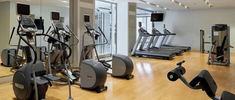 A gym with cardio machines, weight machines, and a mirror wall.