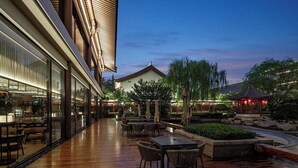 An outdoor patio area with wooden flooring, seating arrangements, and a traditional-style gazebo. - HUALUXE Hotels and Resorts Xi'an Tanghua, an IHG hotel (Xi'an)